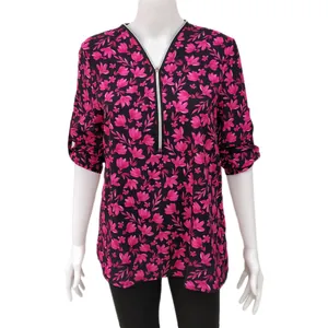 Detailansicht einer pinkfarbenen Bluse mit Blumenmuster und V-Ausschnitt mit Reißverschluss.