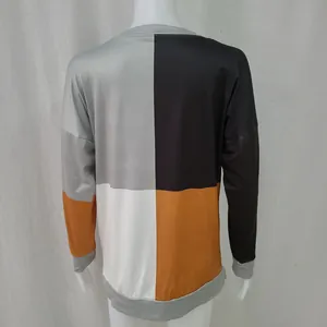 Vista trasera de una sudadera holgada con bloques de color gris, negro y naranja llamativo.