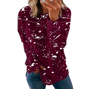 Close-up detail of women's burgundy long sleeve top featuring white graffiti splatter print