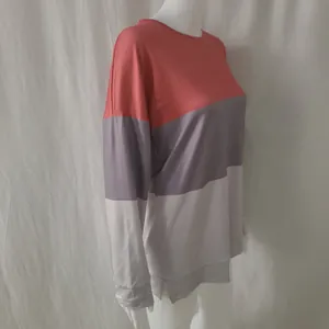 Detail view of a color-block long-sleeve sweatshirt with coral, grey, and white patchwork