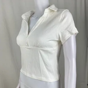 Dettaglio di polo bianca a maniche corte a coste con elegante scollo a V e bottoni fini