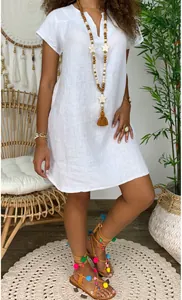 Woman wearing a white boho V-neck short sleeve linen dress in a stylish interior room.