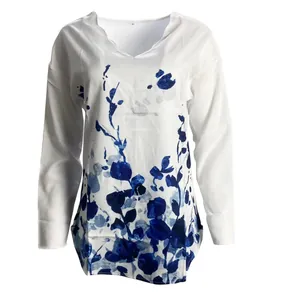Close-up of white long-sleeved shirt featuring blue floral print and wavy V-neckline detail.