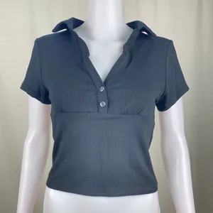 Vista frontale di una polo nera a maniche corte in maglia a costine su un manichino bianco da vetrina