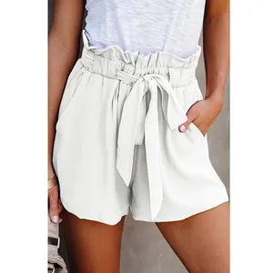 Detail view of white paperbag waist shorts with tied belt and pleated pockets for women.