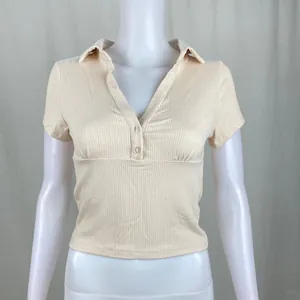 Primo piano di polo a coste a maniche corte da donna beige mostrata su un manichino bianco