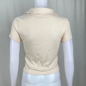 Vista posteriore dettagliata di un crop top polo beige a costine su un manichino bianco