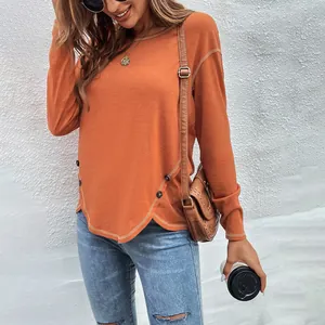Detail shot of casual orange long-sleeved top with irregular hem and button accents.