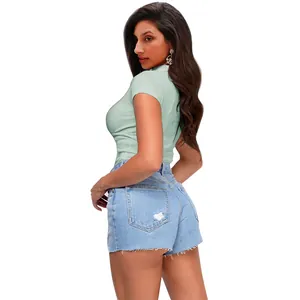Vista laterale di una polo a costine verde chiaro slim fit con pantaloncini di denim