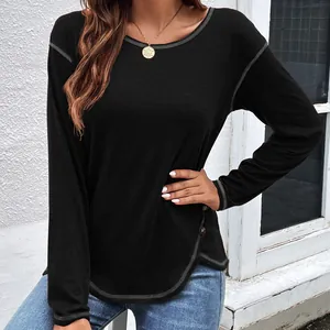 Close-up of black long sleeve T-shirt featuring decorative buttons and irregular hemline.