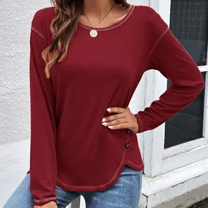 Detail shot of burgundy long sleeve T-shirt featuring buttoned irregular curved hem