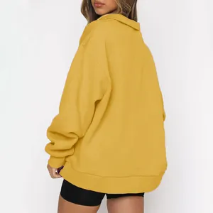 Vista posteriore di una felpa gialla oversize con mezza zip e polsini a costine.