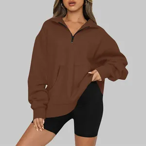 Dettaglio felpa marrone oversize con mezza zip e ampia tasca a marsupio sul davanti