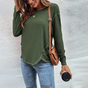 Detail of women's dark green T-shirt with irregular hem and decorative buttons.