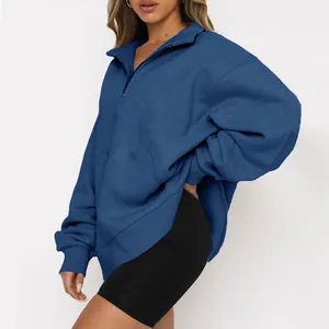 Vista laterale di una donna con felpa blu oversize a mezza zip e pantaloncini neri.