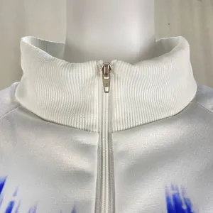 Macro detail view of white ribbed high collar with silver zipper on a gradient sweatshirt.
