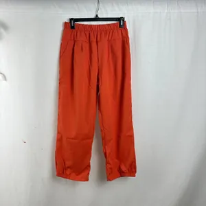 Detail view of orange loose-fit casual trousers with elastic waist for women