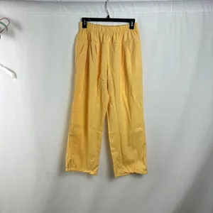 Bright yellow women's high-waisted loose casual pants hanging against white fabric