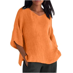 Detail of an orange loose V-neck top with half sleeves and a textured linen-like fabric.