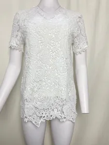 Close-up of white floral lace fabric on a short sleeve top showing intricate crochet details