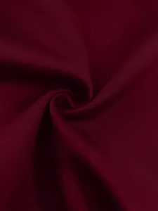 Macro view of burgundy knitted fabric texture showing elegant spiral folds and soft draping