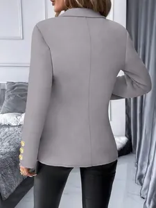 Achteraanzicht van een grijze slim-fit damesblazer met gouden decoratieve knopen op de mouw.