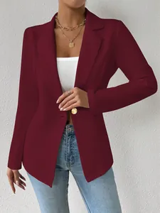Detail van een elegante bordeauxrode blazer met gouden knoop en inkeping in de revers