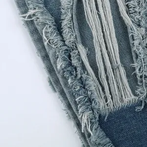 Close-up van de gerafelde en versleten randen van een lichtblauwe gewassen denim short