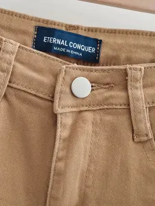 Gros plan d'un jean évasé marron à taille haute avec étiquette de marque et bouton métal