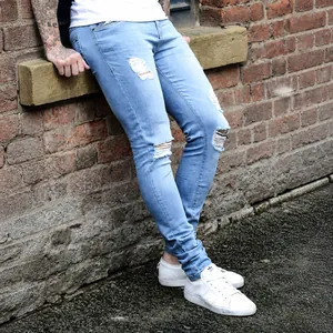 Close-up of light blue distressed skinny jeans for men featuring ripped knee details