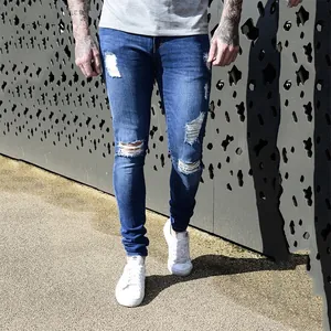 Detail shot of stylish men's slim fit distressed blue jeans featuring ripped knees and wash