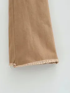 Détail du bas d'un jean évasé marron rétro avec une finition à bords effilochés