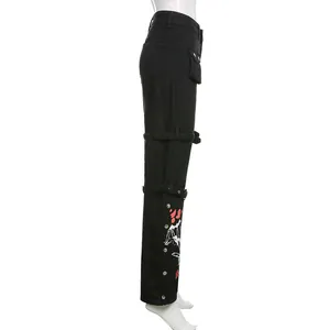 Zijdetail van de zwarte streetstyle cargo jeans met rode print en metalen gespen