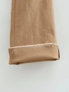 Gros plan détaillé de l'ourlet effiloché de ce jean évasé rétro de couleur camel