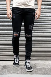 Detailed view of men's black ripped skinny jeans with distressed finish and knee holes