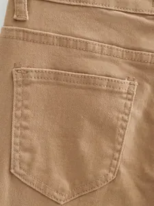 Gros plan sur la poche arrière et la texture d'un jean évasé de couleur kaki vintage