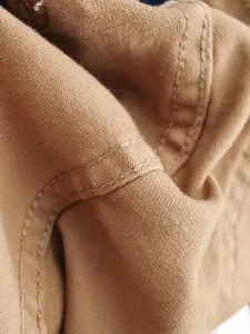 Gros plan détaillé du tissu denim marron montrant une couture double très robuste