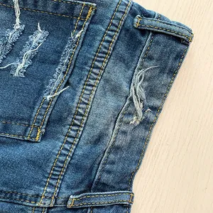 Nahaufnahme von zerrissenen Jeans-Shorts mit gelben Kontrastnähten und Distressed-Look.
