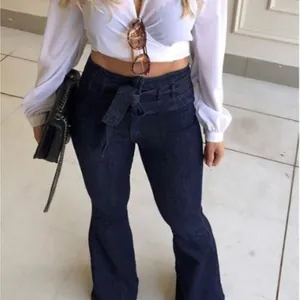 Jean évasé à taille haute pour femme avec ceinture à nouer élégante et moderne.