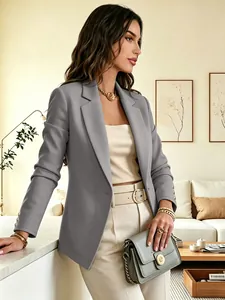Sophisticated detail of a grey women's blazer featuring gold sleeve buttons in a room.