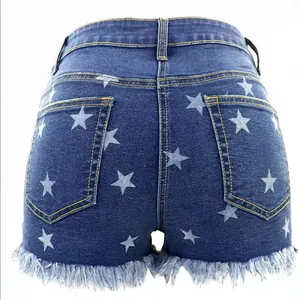 High-waisted dark blue denim shorts featuring white star prints and a stylish frayed fringe hem