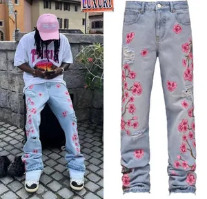 Detail view of men's straight jeans with cherry blossom embroidery and distressed rips
