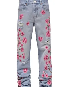 Men's light blue straight-leg jeans with pink cherry blossom embroidery and ripped details.