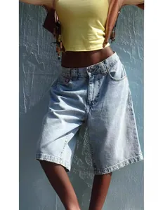 Close-up of women's slim fit light blue denim bermuda shorts shown on model outdoors