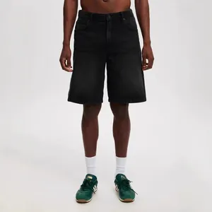 Men's black denim shorts on model, styled with white socks and green retro sneakers.