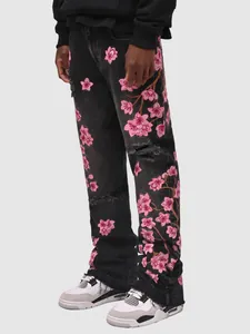 Detailed macro view of pink cherry blossom embroidery on black straight-leg men's denim jeans