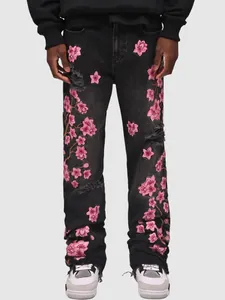 Detail view of men's black straight jeans with intricate pink cherry blossom embroidery