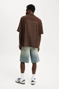 Back view of premium men's faded denim shorts styled with white socks and casual sneakers