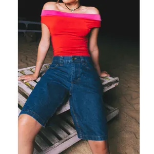 Detail of women's slim fit dark blue denim Bermuda shorts in beach setting