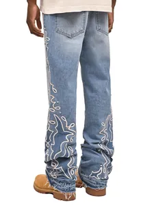 Dettaglio jeans larghi da uomo con ricamo bianco e decorazioni in strass
